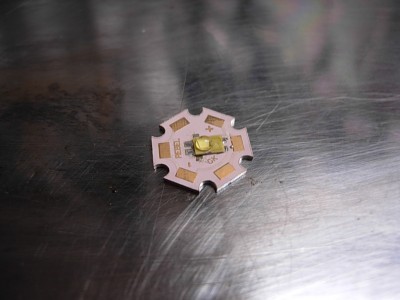 Dann das Bügeleisen anheizen, bis das Lötzinn weich ist und<br />dann die REBEL mit einer Messerspitze oder einer Pinzettenspitze<br />vorsichtig andrücken, so das sie Kontakt mit der Platine hat und<br />das Lötzinn beide Teile miteinander verbindet.<br />(Aber vorsichtig, das die REBEL nicht verrutscht!!)